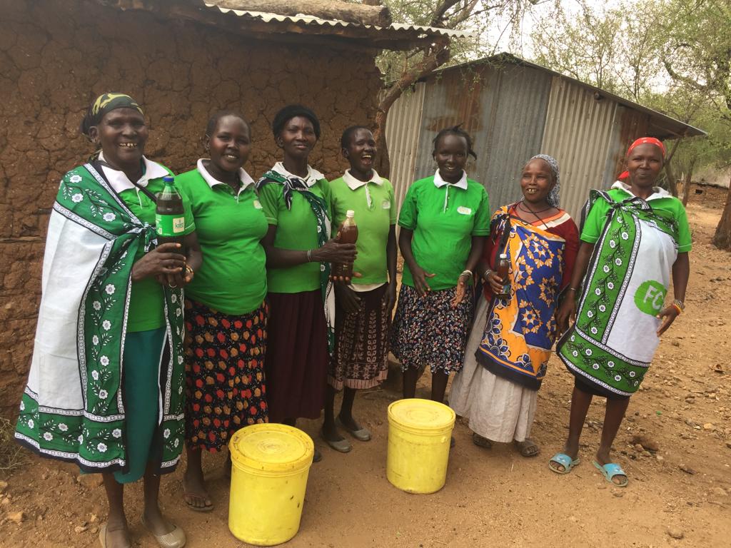 A group of women from Kerio Valley, with 2 buckets of harvested honey.