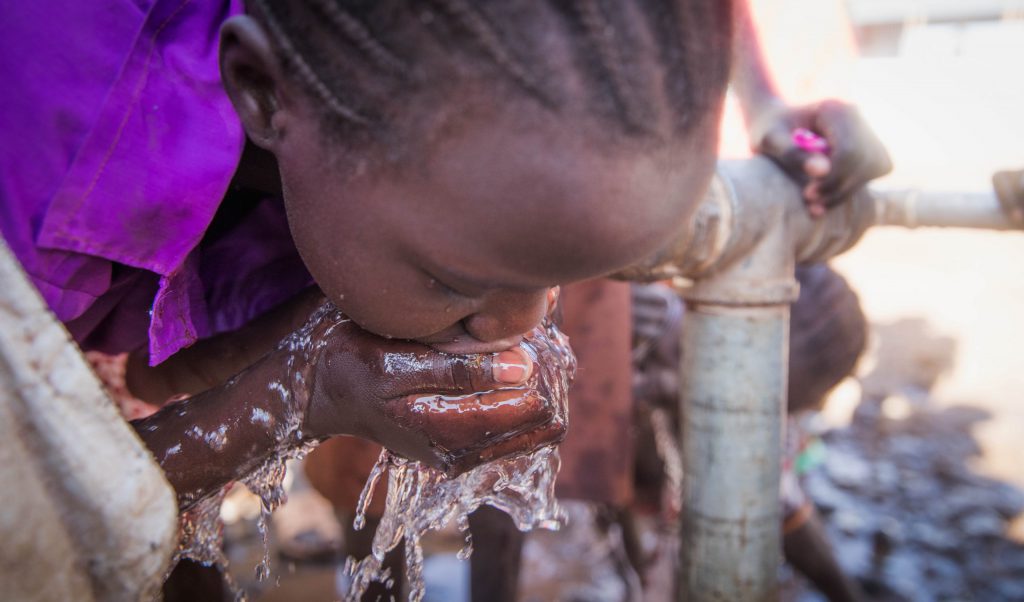 Girl drinking from a water pump