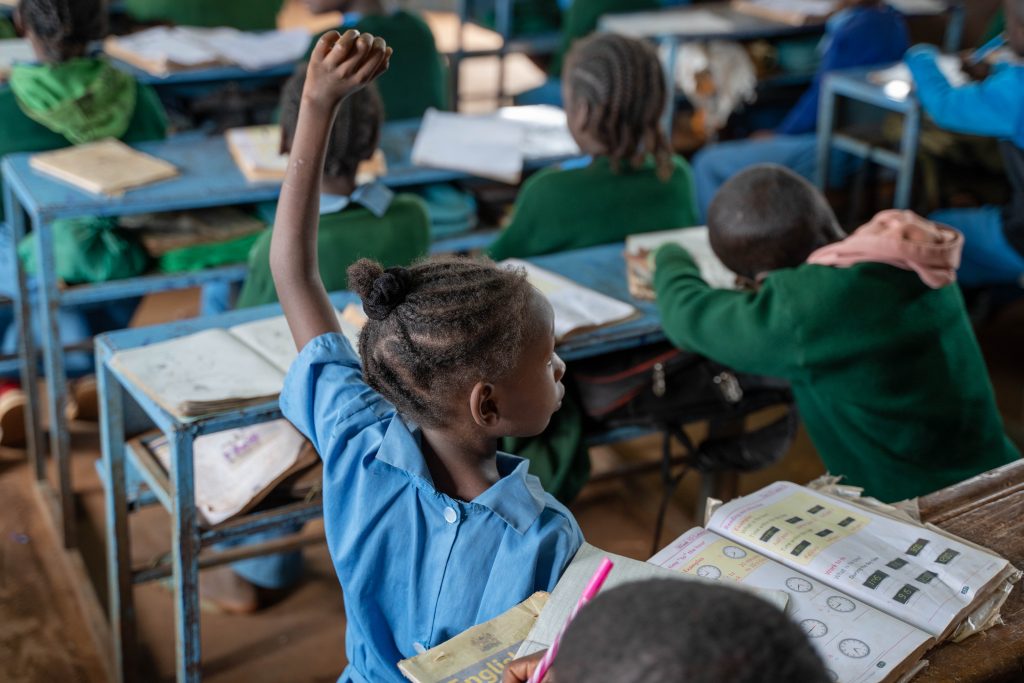 A girl raising her hand to answer a question in class