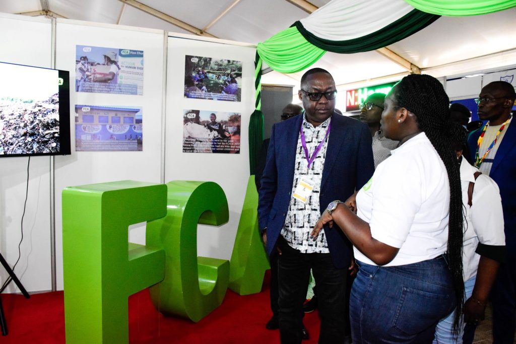A man standing in front of FCA exhibition stand having a conversation with a lady.