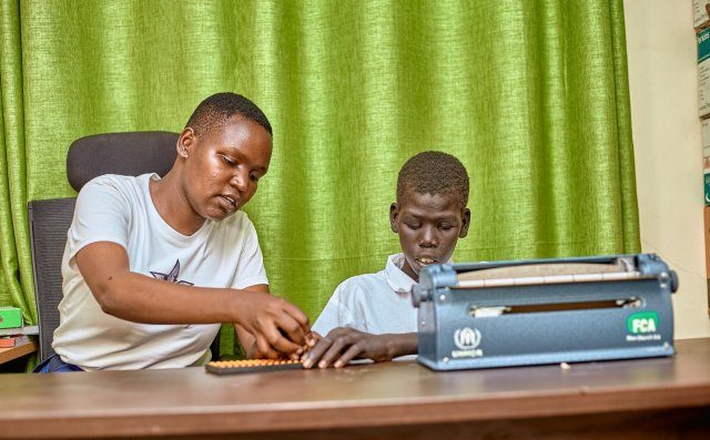 Valentine Moige, a special needs teacher at Joy Primary School, teaches Steven Both how to use Braille machine.