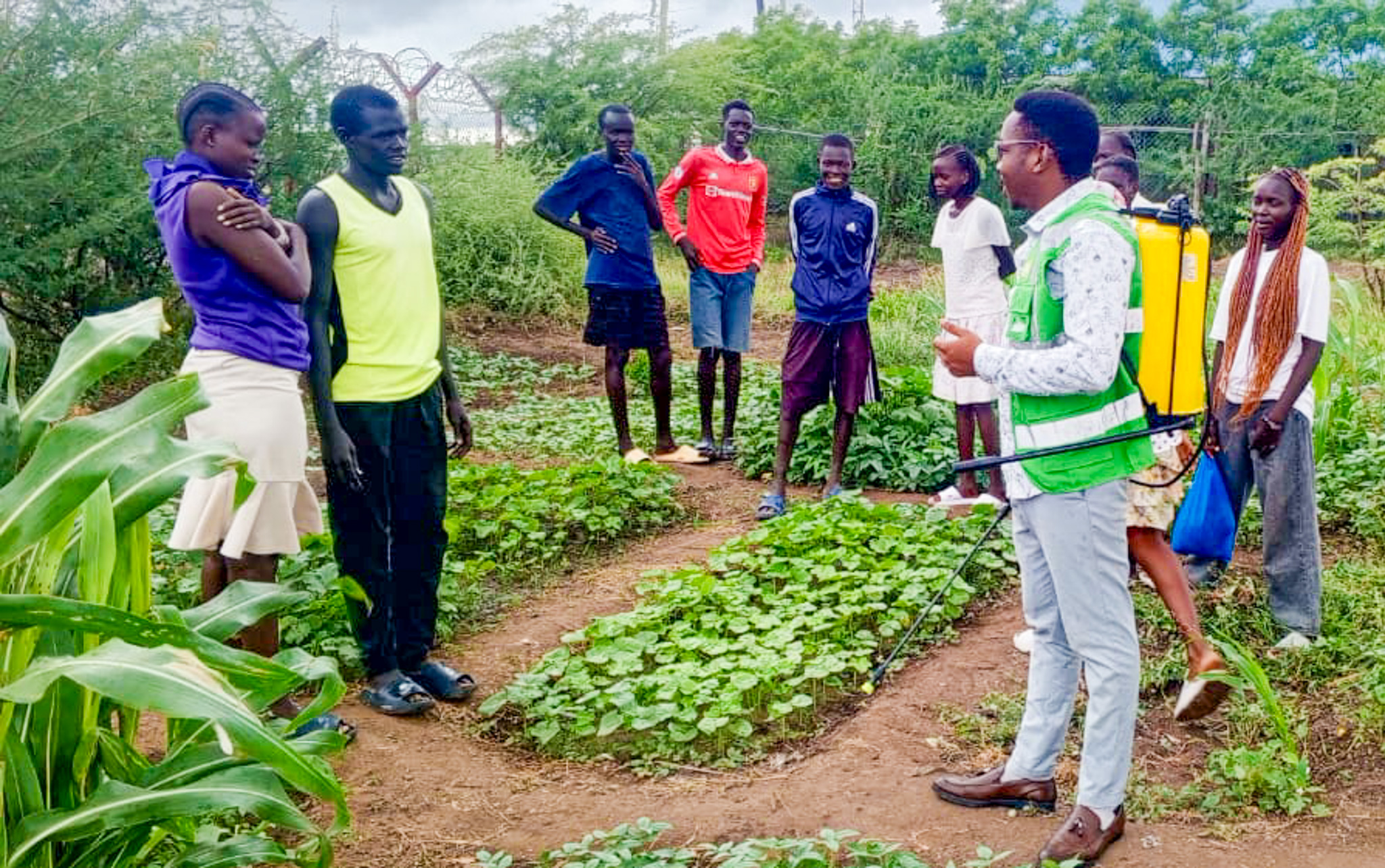 Students from Bright Star Secondary with their teacher in the kitchen garden, learning how to grow food and protect the environment.